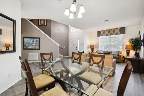 Glass-top dining table with the living room and staircase beyond