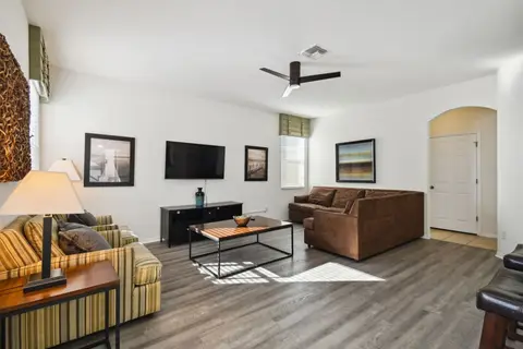 Living room with a sectional, a striped armchair, and a wall-mounted TV