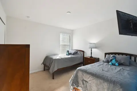 Two twin beds with gray bedding and a dresser
