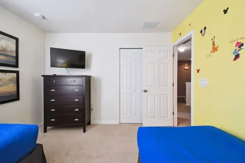 Twin bedroom with a yellow accent wall and a wall-mounted TV