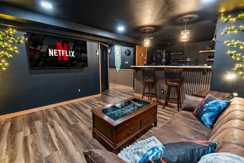 Sectional with dragon pillows facing a wall-mounted TV, beside the river bar