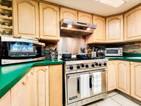 Six-burner range with pots on, beside the microwave and toaster oven