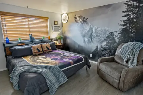 King bedroom with a wolf forest mural, wolf bedding, and a leather recliner