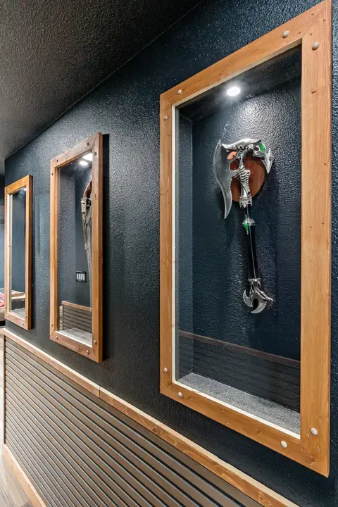 Hallway lined with lit, recessed weapon display cases
