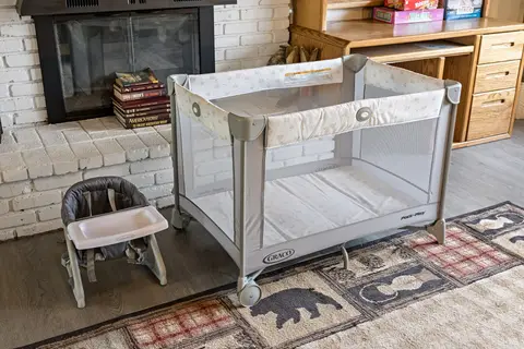 Pack ’n Play and a strap-on high chair by the fireplace