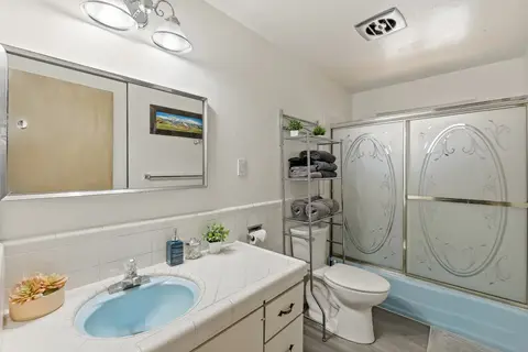 Bathroom with a blue sink, a tub with glass doors, and a towel rack