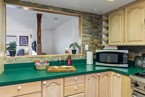 Kitchen pass-through to the living room, with a stacked stone backsplash