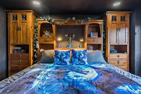 King bed framed by oak wardrobes and shelves in the dragon room