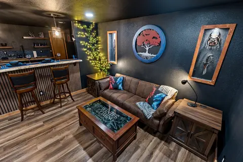 Fantasy-wing living room with a painted tree crest and lit weapon displays