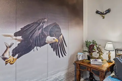 Eagle mural above an antique side table and a lamp