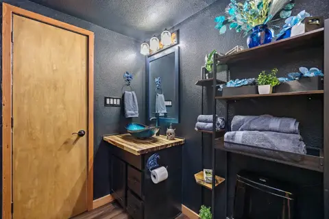 Bathroom with dragon towel rings, a blue vessel sink, and open shelving