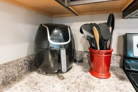 Air fryer and a crock of cooking utensils on the counter