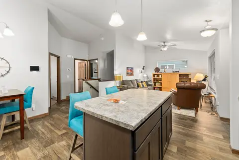 Kitchen island with teal stools beside the dining table and living room