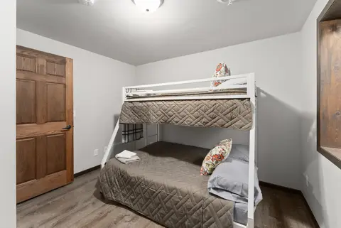 Twin-over-full bunk bed with a ladder beside a wood door