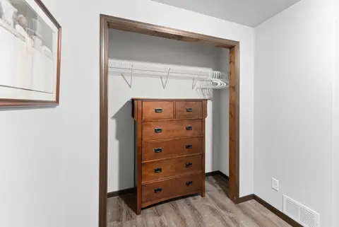 Closet with a wood dresser and a wire shelf