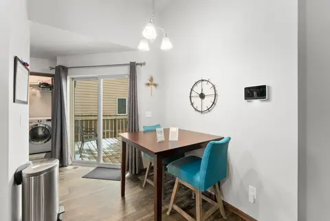 Dining table with teal chairs beside a sliding glass door to the deck