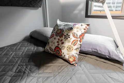 Lower bunk with gray bedding and a floral pillow
