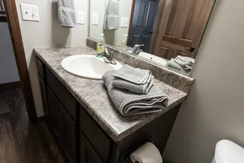 Bathroom vanity with folded gray towels and a wide mirror