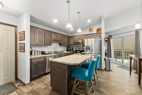 Kitchen and dining area with teal chairs and a sliding door to the deck