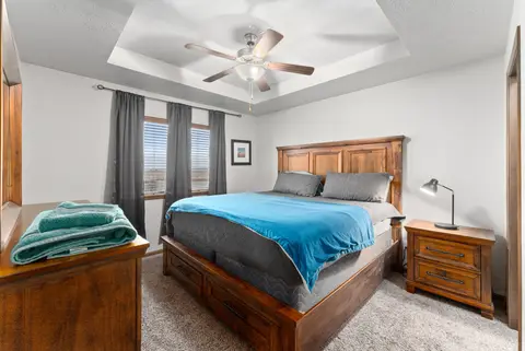 King bedroom with a tray ceiling, a dresser, and dark curtains
