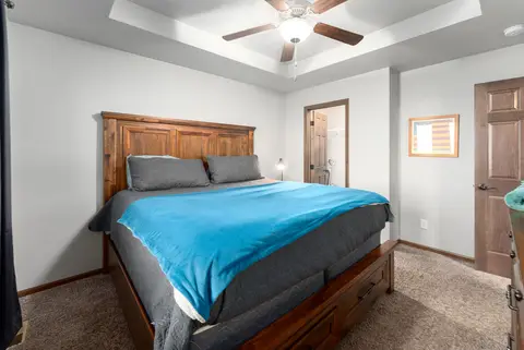 King bedroom with a wood headboard, a blue throw, and a ceiling fan