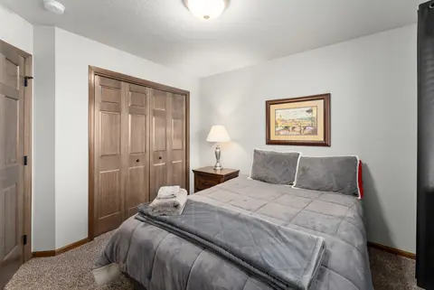 Bedroom with a gray comforter, wood closet doors, and a framed print