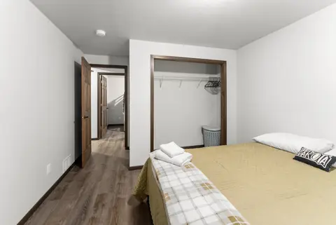Bedroom with a plaid throw and an open closet with hangers