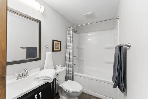 Bathroom with a tub and shower, a gray curtain, and a framed print