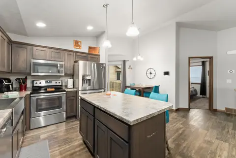 Kitchen island with a stone-look counter, a stainless range, and a refrigerator