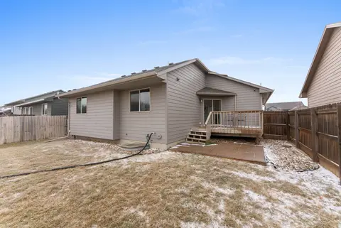 Back of the house with the deck steps and a fenced lawn