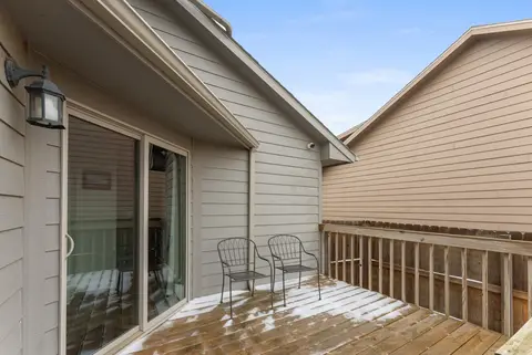 Deck with two metal chairs beside a sliding glass door