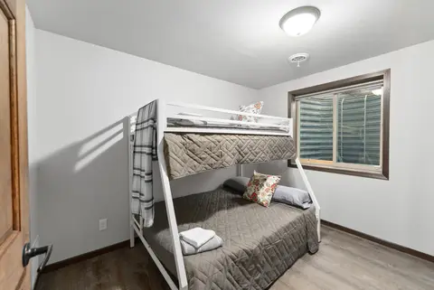 Bunk room with a white twin-over-full bunk bed and gray bedding