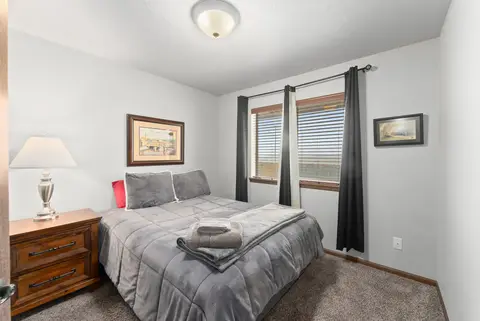 Bedroom with a gray comforter, a wood nightstand, and dark curtains