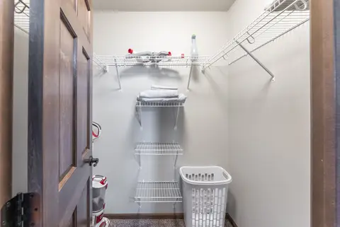 Walk-in closet with wire shelves, spare linens, a vacuum, and a laundry basket