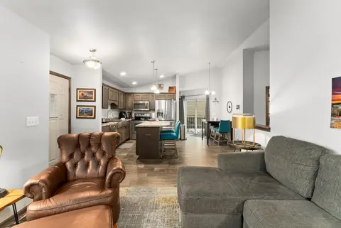Open living room with a leather armchair and a sectional, looking into the kitchen and dining area