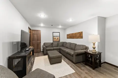 Den with a gray sectional, an ottoman, and a TV