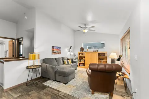 Living room with a gray sectional, a leather armchair, a wood hutch, and a ceiling fan