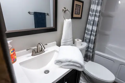 Vanity with a white sink, folded towels, and a towel ring