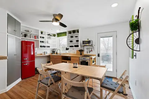 Kitchen table with folding chairs beside the red fridge and open shelves