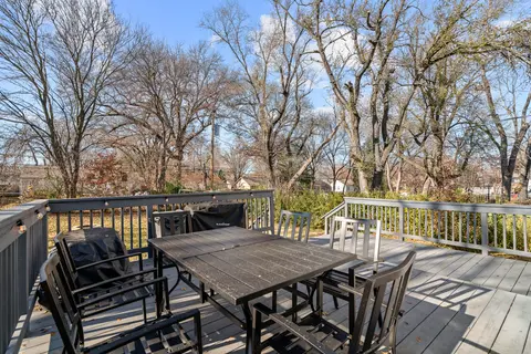 Deck dining table and chairs under tall bare trees