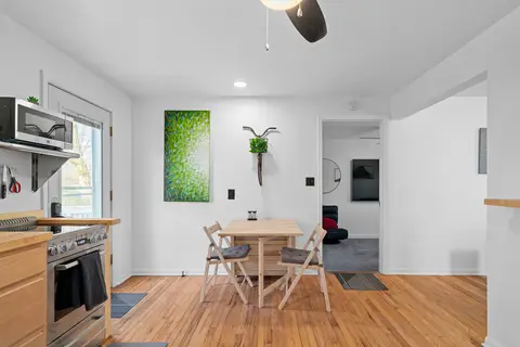 Small dining table and chairs by the kitchen, below a green painting