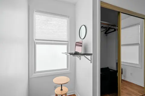 Wall-mounted desk and a stool by the window, next to a mirrored closet