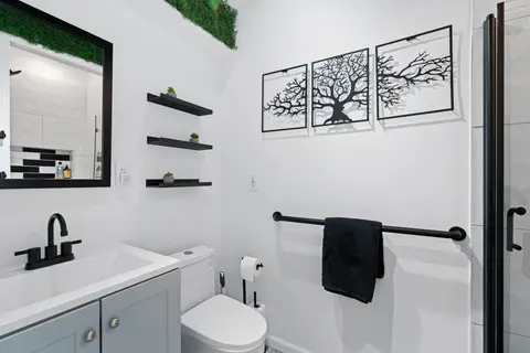 Bathroom with a gray vanity, black fixtures, and tree wall art