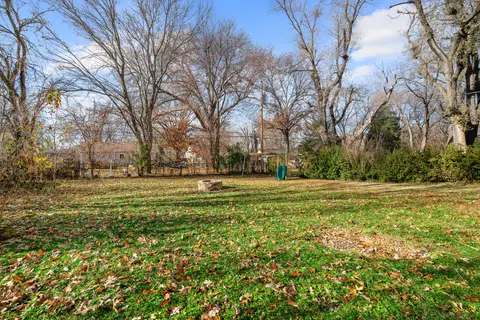 Open backyard lawn bordered by shrubs and trees