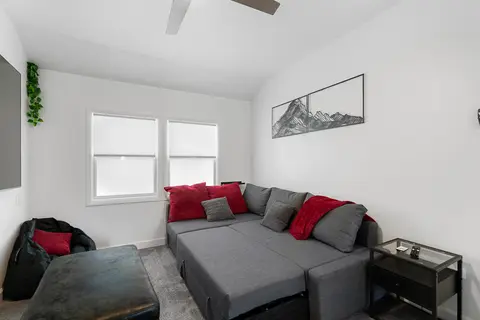 Den with a gray sectional, red pillows, and a side table