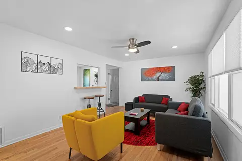 Living room with gray sofas, a yellow armchair, and a red rug under a ceiling fan