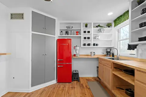 Kitchen with a red fridge, tall gray pantry cabinets, and wood counters