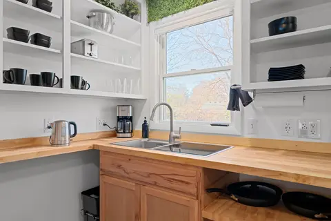 Open shelves of dishes and mugs above the sink and a coffee maker