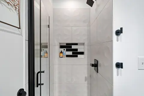 Walk-in glass shower with white tile and black fixtures