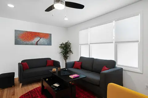 Two gray sofas with red pillows around a coffee table, beside a large window